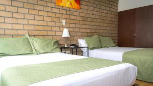 马尼萨莱斯Hotel Portal de Milán的酒店客房带两张床和砖墙