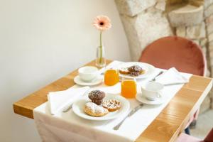 桑格罗堡Garni il Concale的桌子上放有甜甜圈和橙汁的盘子