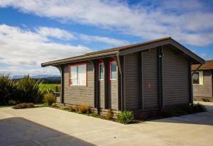 Little WanganuiLittle Wanganui Hotel的车道旁的一间棕色小房子,设有红色窗户