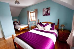 Achill Sound阿基尔度假屋的一间卧室配有两张紫色毯子的床