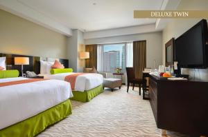 马尼拉Acacia Hotel Manila的酒店客房设有两张床和一台平面电视。