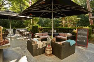 布雷达Parkhotel Mastbosch Breda的一个带沙发和遮阳伞的户外庭院