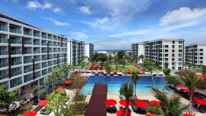 华欣华欣阿玛瑞度假酒店的享有带游泳池和红伞的度假村的空中景致