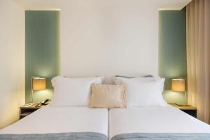 法蒂玛SDivine Fatima Hotel, Congress & Spirituality的一张带白色床单和枕头的床