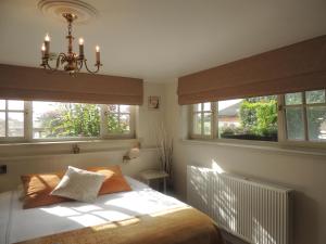 米德尔克尔克Bed & Breakfast Het Zilte Zand - Westende - Middelkerke - De Kust的一间卧室配有一张带两个窗户和吊灯的床。