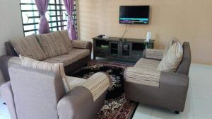 甲抛峇底Nurul Homestay的客厅配有两张沙发和一台电视机
