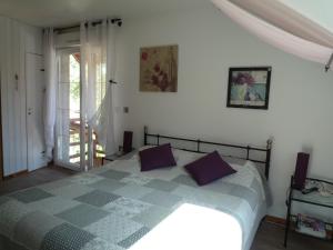 博讷Le Verger du Sausset的一间卧室配有一张带紫色枕头的床