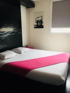 Yvrac波尔多东卡迪尼亚酒店的一间卧室配有一张带粉色毯子的大床