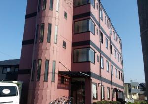 大村市Omura - Hotel / Vacation STAY 46227的一座高大的粉红色建筑,有很多窗户