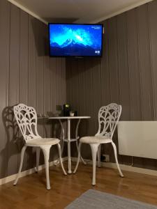 莱克内斯Cozy & private room in the middle of Lofoten的两把椅子和一张桌子,墙上配有电视