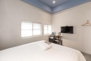 台东门廷若室旅店-铁花秀泰馆的一间白色卧室,配有床和电视
