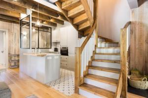 GessaLuderna - Dúplex con jardín des Treuetes的带木制楼梯的厨房和带白色橱柜的厨房