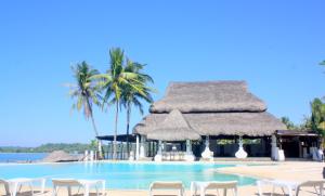 CurrimaoPlaya Tropical Resort Hotel的一个带椅子和棕榈树的度假村游泳池