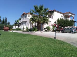 斯卡拉卡伦尼斯ilyda Residence apts的一座白色的房子,有棕榈树和停车计