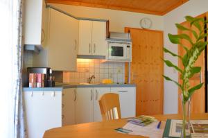 BirkfeldFerienwohnungen Perhofer的厨房配有白色橱柜和木桌