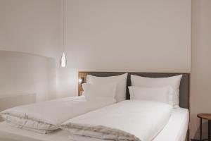 梅拉诺Kuntino Suites的白色的床、白色床单和枕头