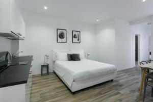 米兰Milanofierapartments的白色的卧室配有白色的床和一张桌子