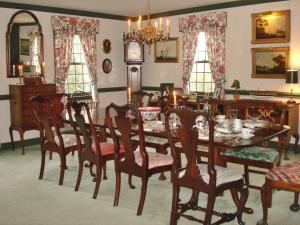 威廉斯堡Newport House Bed & Breakfast的一间带桌椅和时钟的用餐室
