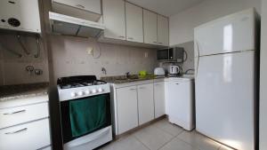 圣达菲Apartamento 4 de Enero的厨房配有白色橱柜、炉灶和冰箱。