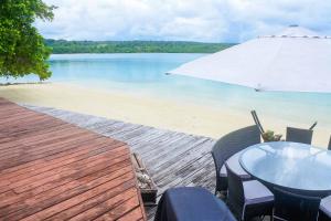 卢甘维尔Santo Sunset Beach Villas on Surunda Bay的海滩上的桌椅和遮阳伞