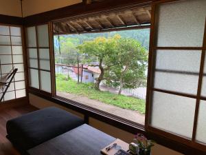 田边市Private GUEST HOUSE KUMANOYASA的一间窗户的房间,俯瞰着一棵树