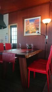 富士吉田市Tsukitei1的酒吧设有两把红色椅子和一张带酒杯的桌子
