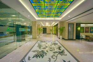 贾姆穆Lemon Tree Hotel Jammu的大堂拥有色彩缤纷的天花板,走廊上铺有地毯。