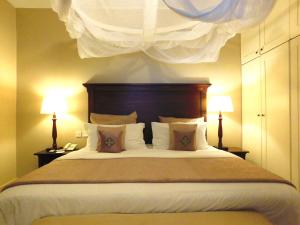 内罗毕普拉希那公寓及套房酒店的一间卧室配有一张大床和两盏灯