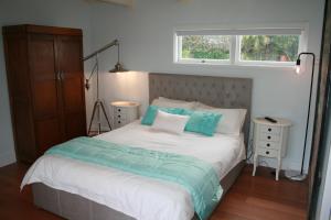奥克兰The Boat House的一间卧室配有一张带蓝色枕头的床和一扇窗户。