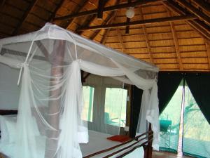 Grietjie Game ReserveMuweti Bush Lodge的卧室配有带窗户的白色天蓬床