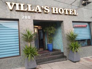 圣保罗Villas Hotel的一座建筑前有两株盆栽植物的酒店