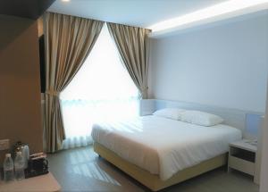 怡保Legacy Hotel Ipoh的卧室设有白色的床和大窗户