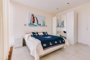 包道乔尼托毛伊Villa Georgina的白色卧室配有一张带蓝色毯子的床