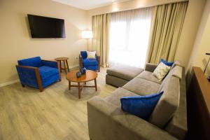 CharataPLATINUM HOTEL CASINO的客厅配有沙发和2把蓝色椅子