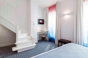 巴黎34B酒店 - 阿斯托利亚酒店的一间卧室配有一张床、一张书桌和一个楼梯