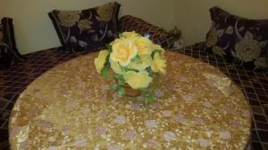 TahlaAuberge de Tabhirte的一张花瓶,上面有黄色的花朵,坐在桌子上