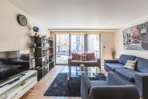 伦敦Lovely 2 Bed 2 Bath Apartment Central London的客厅配有蓝色的沙发和电视