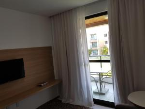 拉巴拉德纳圣米格尔Iloa Residence Resort - Barra de São Miguel的客房设有电视和带阳台的窗户。
