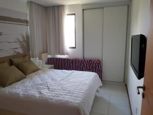 拉巴拉德纳圣米格尔Iloa Residence Resort - Barra de São Miguel的一间卧室配有一张床和一台平面电视