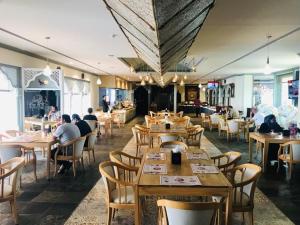 马斯喀特苎麻集团盖斯特林酒店的一间设有木桌的餐厅,有人坐在餐厅里
