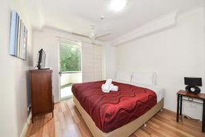 布里斯班芬达花园公寓的一间卧室配有一张带红色毯子的床
