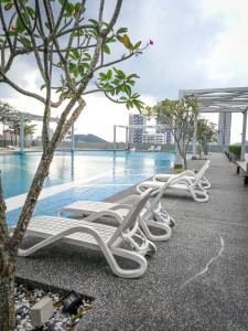 科塔达曼萨拉Gt Home encorp strand residence (alpha ivf )的游泳池旁的一排白色躺椅