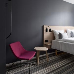 卑尔根Citybox Bergen City的一间卧室配有一张床和一张粉红色的椅子