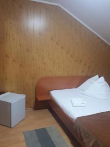 TrăisteniPensiunea Valea Negrasului的一间卧室设有一张床和木墙