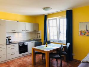宾茨Villa Sanddorn的一间带桌子的厨房和一间带黄色墙壁的厨房