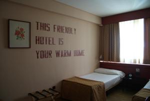 马德里阿纳科酒店的卧室配有一张床,墙上有标志