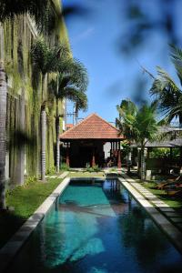 登巴萨恒河酒店公寓 的棕榈树屋前的游泳池