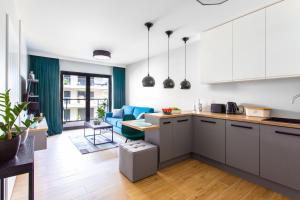 济夫努夫Apartament Gardenia Sea&Sun DZIWNÓW PRZY PLAŻY的开放式厨房以及带蓝色沙发的客厅。