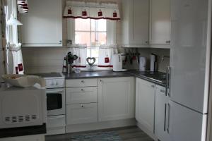 斯塔姆松Tinabua Rorbu Lofoten的白色的厨房配有白色橱柜和窗户