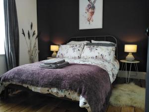 考布里奇Aubrey Cottage的一间卧室配有一张带紫色棉被的床和两盏灯。